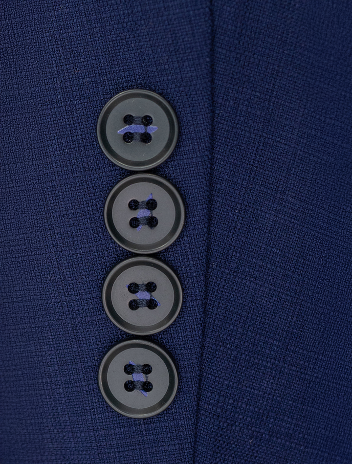 Close-up of the FUBU Berry Blue Vested Suit by Fubu The Colle, showcasing a navy blue fabric in a slim fit with four vertically aligned dark blue buttons.