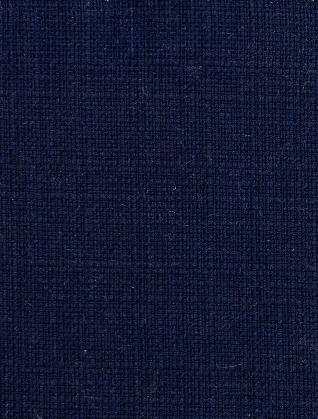 Detailed view of the FUBU Berry Blue Vested Suit by Fubu The Colle, featuring a navy blue textured fabric with a subtle crisscross pattern, ideal for crafting a modern fit suit.