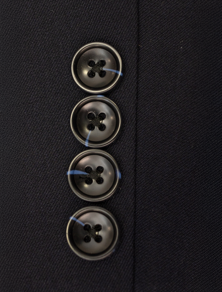 Close-up of four black buttons sewn vertically on dark fabric, characteristic of the FUBU Midnight Navy with Debossed Windowpane Vested Suit by Fubu The Colle.