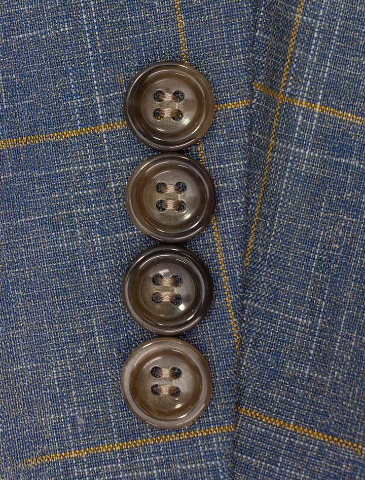 Close-up of four brown buttons on the cuff of a slim-fit FUBU Steel Blue with Mustard Windowpane 2-Piece Suit by Fubu The Colle.
