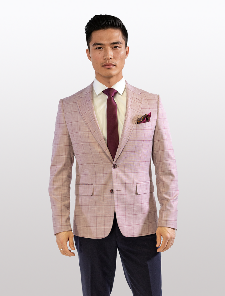 A man stands against a white background in a Fubu The Colle FUBU Rose with Cherry Windowpane Sport Jacket, paired with a white shirt and maroon tie.