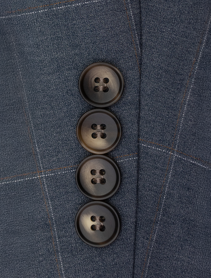 Close-up of four black buttons on the blue textured fabric of the FUBU Gravel Blue with Peach Windowpane 2-Piece Suit by Fubu The Colle, arranged vertically, typical of a modern fit design.
