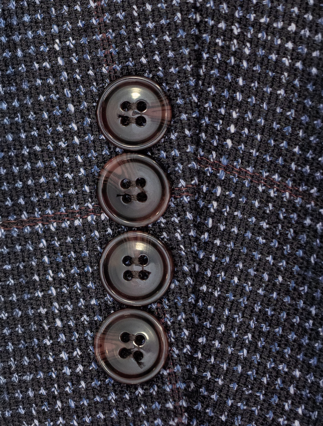 Close-up of four dark buttons on a textured fabric, echoing the polished elegance of the FUBU Textured Navy with Brick Windowpane Sport Jacket by Fubu The Colle, arranged vertically.