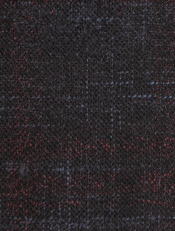 A close-up of the FUBU Midnight Navy with Wine Windowpane Sport Jacket from Fubu The Colle showcases a dark textured fabric with subtle red and blue specks, echoing the elegance typical of slim fit sport coats.