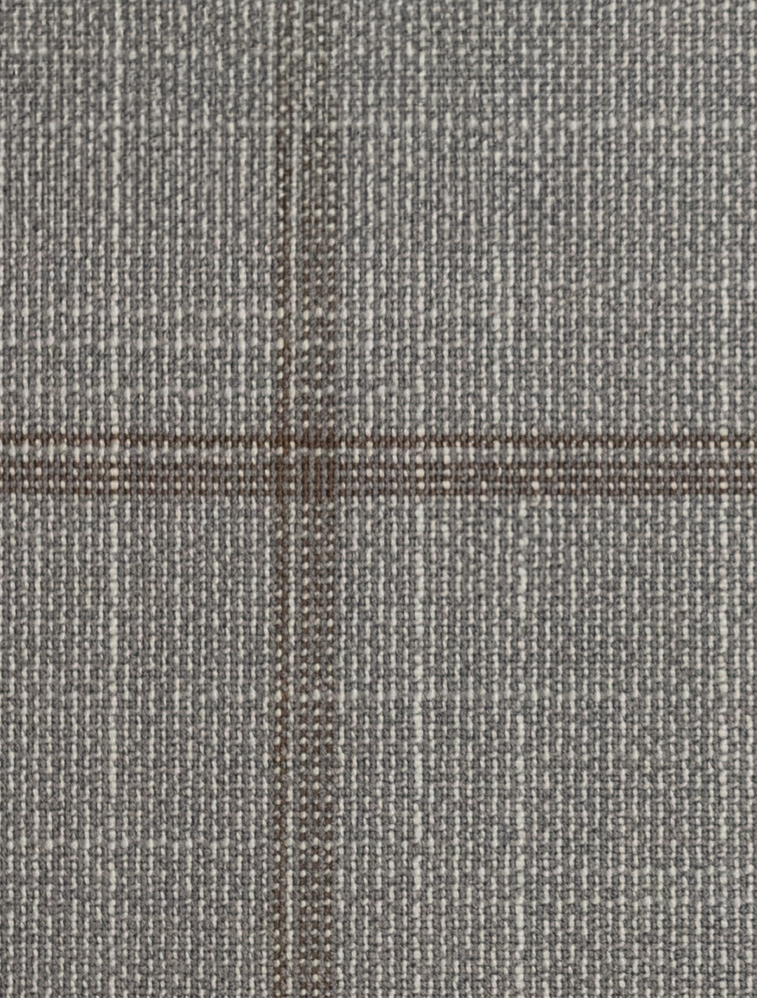 A close-up of the FUBU Oat Grey with Brown Windowpane Peak Lapel 2-Piece Suit by Fubu The Colle showcases a refined gray woven fabric with a subtle checkered pattern, perfect for a Slim Fit suit, featuring intersecting dark and light threads made of Tetron Rayon.