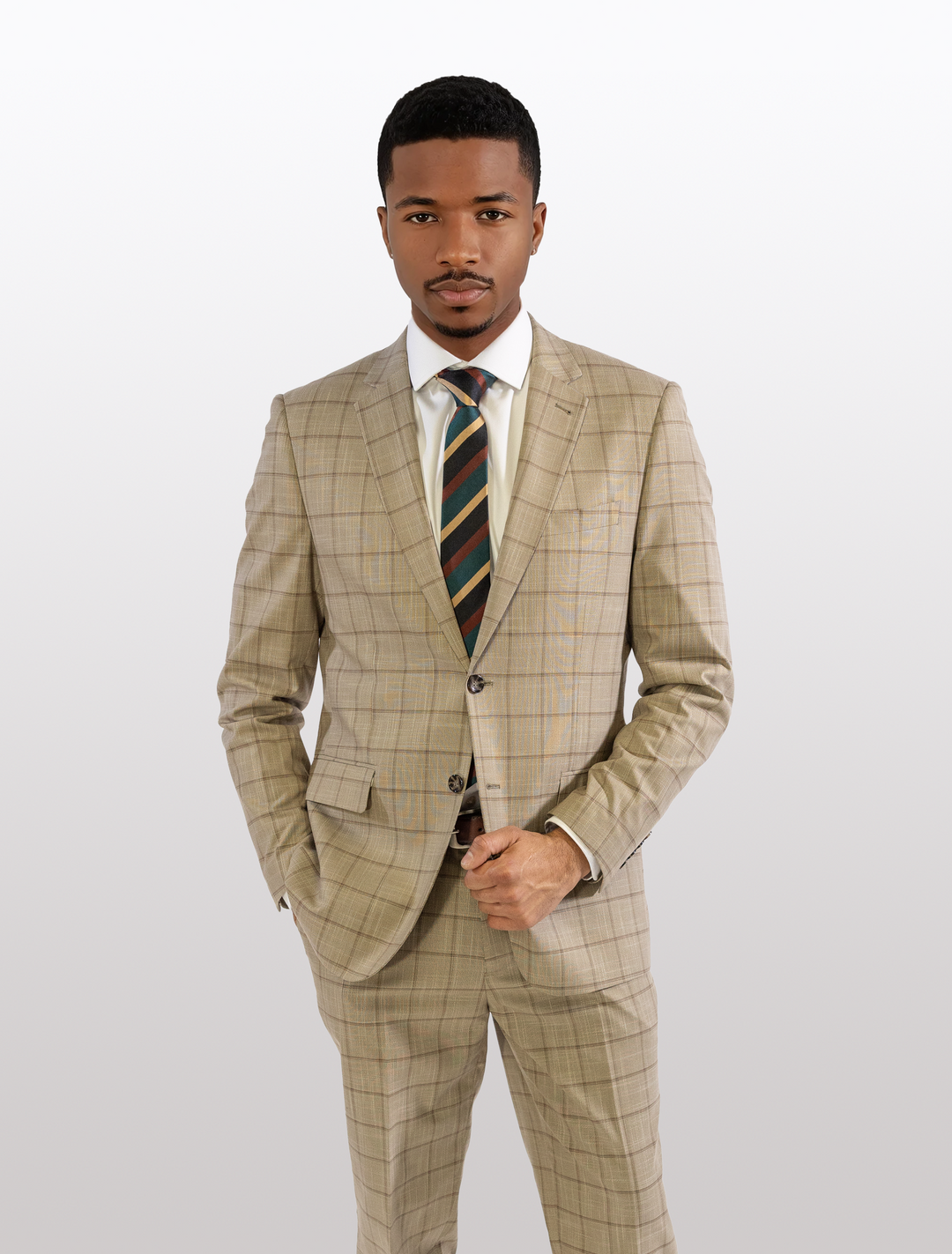 A person in the FUBU Camel with Mocha Windowpane 2-Piece Suit, featuring a modern fit and stretch armholes for added comfort, stands against a plain background, facing forward with one hand in pocket.