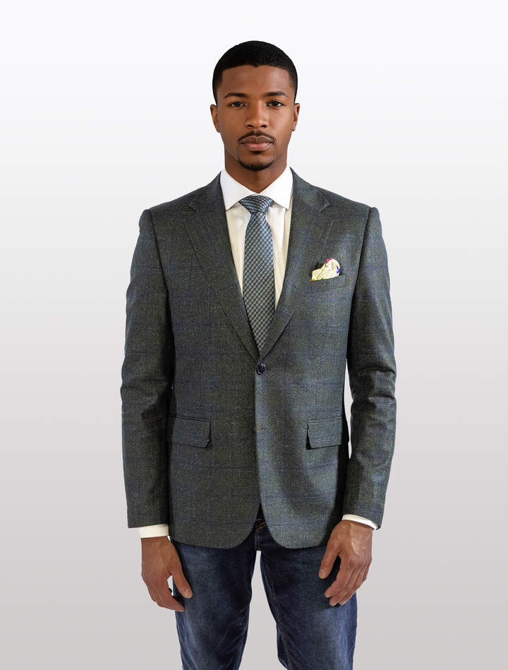 Stylishly posed, a person dons the FUBU Deep Olive with Navy Windowpane Sport Jacket by Fubu The Colle over a crisp white shirt and tie. Complemented by jeans, this look effortlessly mixes the casual charm of Karako Suit stores with sport coat sophistication.