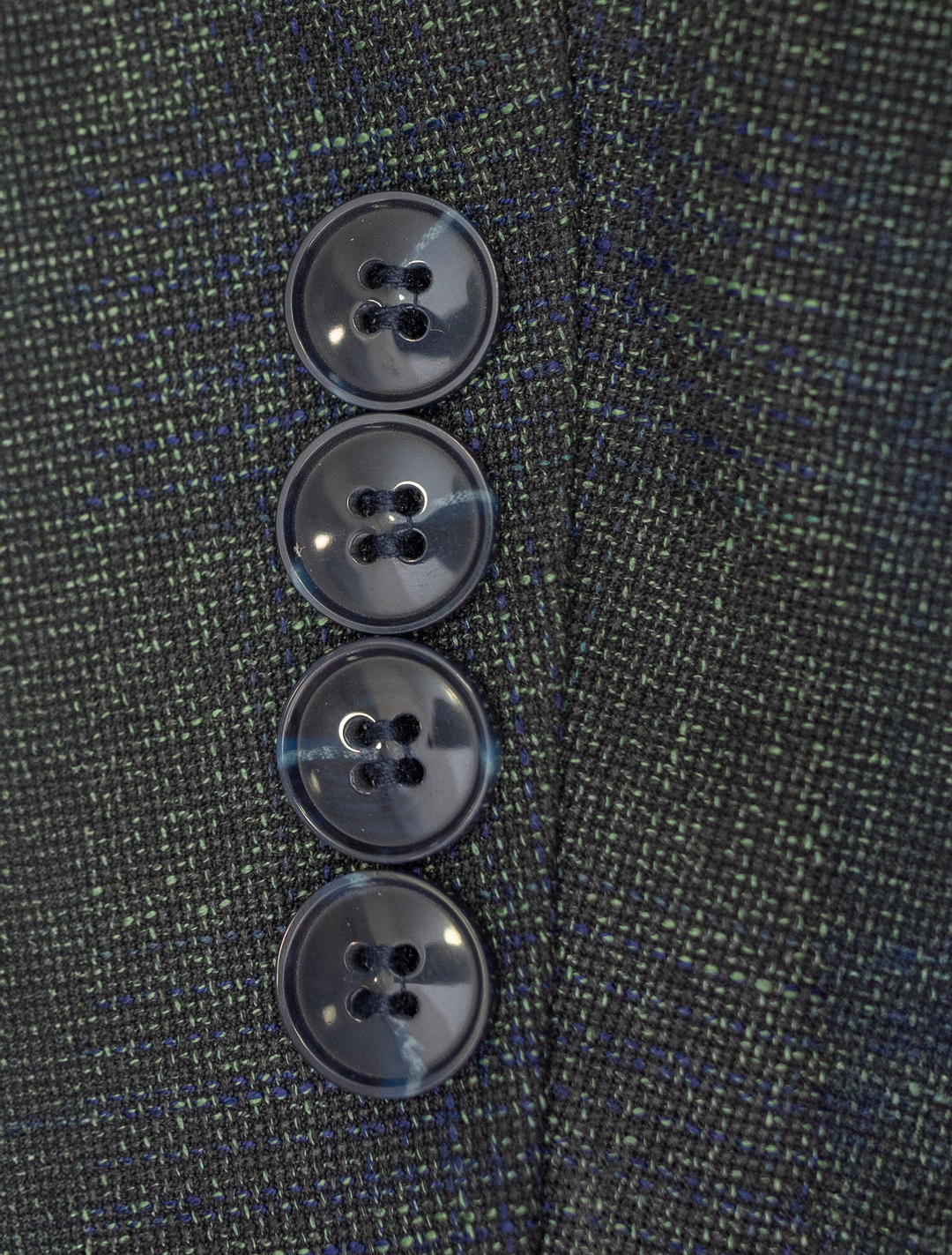 Close-up of four dark buttons on the sleeve of a FUBU Deep Olive with Navy Windowpane Sport Jacket, showcasing the timeless elegance typical of Fubu The Colle.