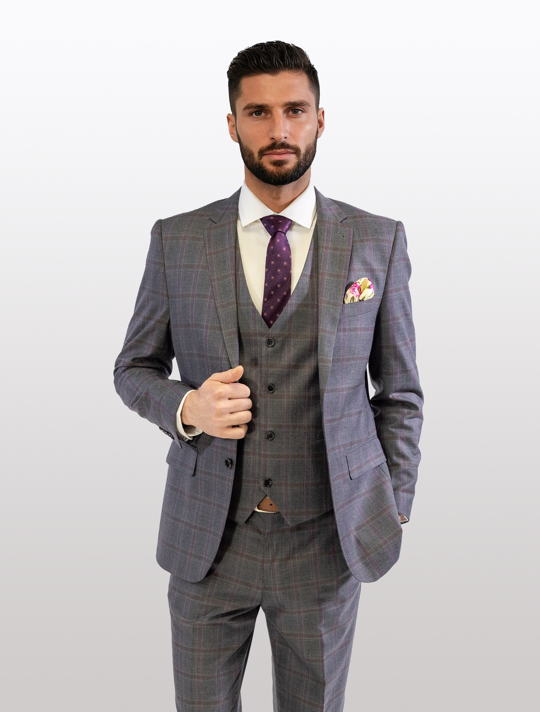 A man poses against a plain background wearing the FUBU Charcoal with Purple Windowpane Vested Suit by Fubu The Colle, paired with a white shirt and purple tie.