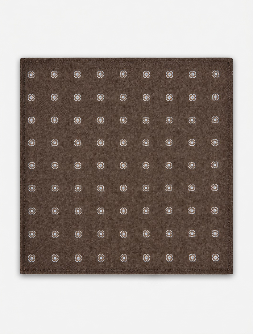 Crafted by Karako Collecti, the Bronze Floral Pocket Square Handkerchief showcases a bronze square microfiber fabric adorned with a grid of small, evenly spaced white and grey floral motifs. Displayed on a plain white background, this stylish men's accessory is wrinkle-resistant, offering everyday elegance.