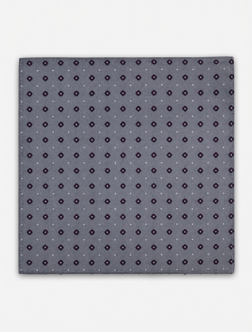 The Karako Collecti Medium Grey with Wine Pocket Square Handkerchief features a refined pattern of small dark purple and white geometric shapes evenly distributed across its gray microfiber fabric, offering an elegant formal accessory suitable for any occasion.