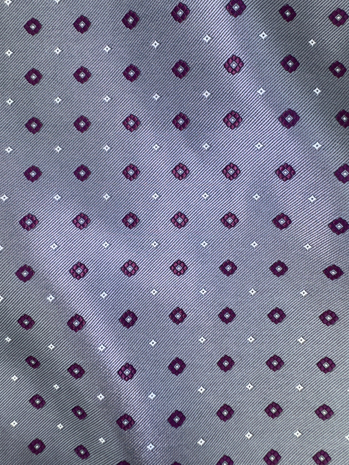 Close-up of the Karako Collecti Medium Grey with Wine Pocket Square Handkerchief, showcasing a repeating pattern of small maroon and white geometric shapes on a gray background—an ideal formal accessory for any modern ensemble.