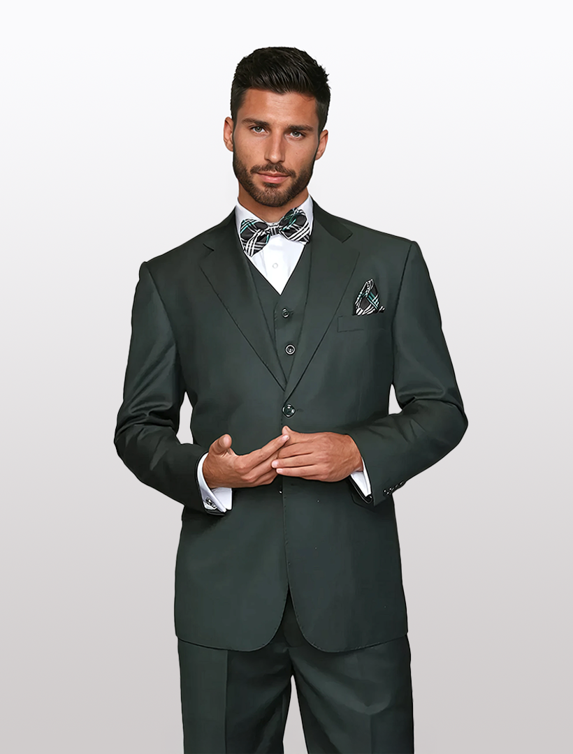 A man poses against a plain backdrop wearing the Statement Men's Solid Hunter Green Wool Blend Vested Suit (Tailored Fit), accessorized with a patterned bow tie and pocket square.