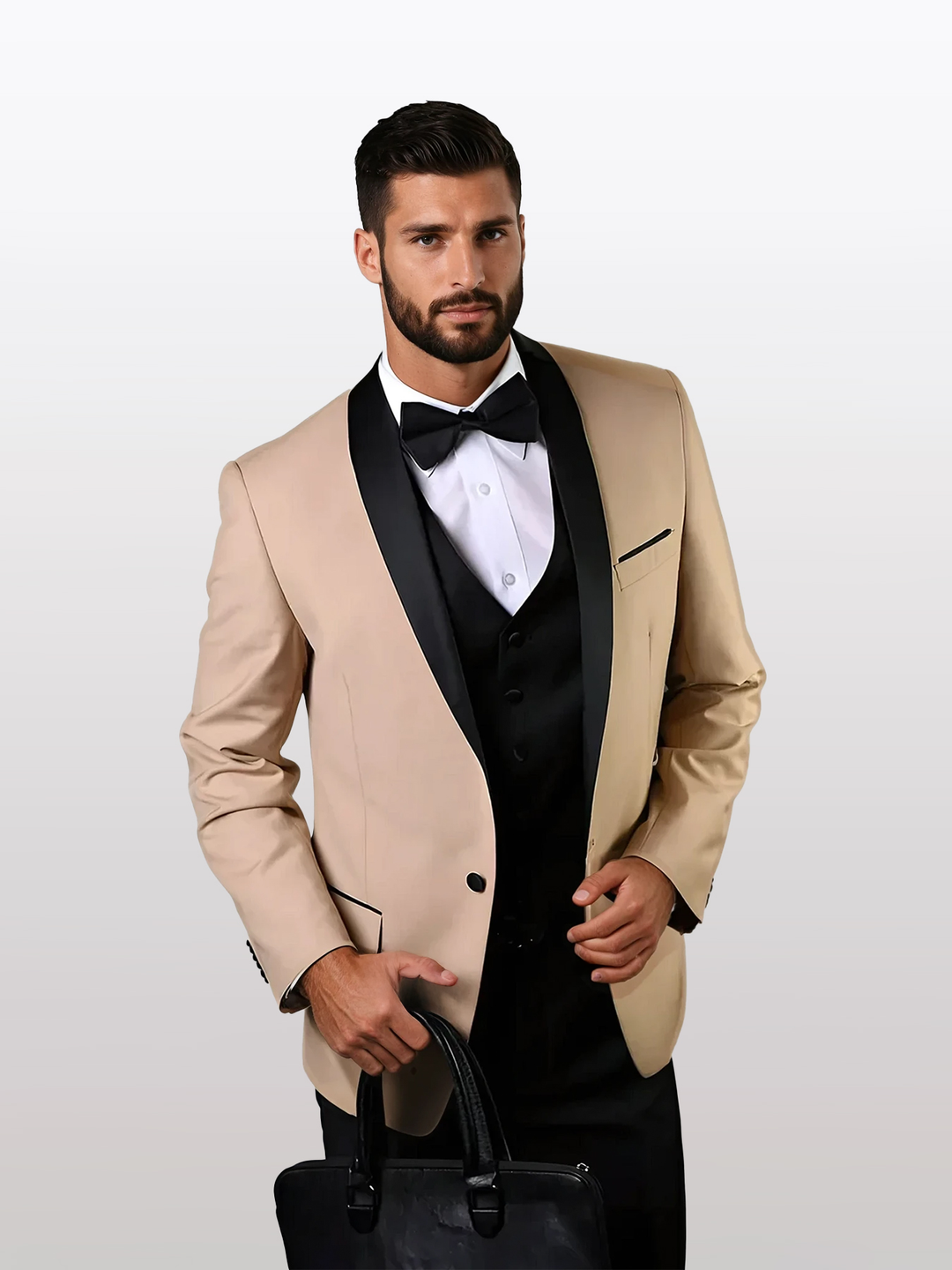 A man in a Statement Men's Champagne with Black Lapel Vested 100% Wool Tuxedo, featuring a beige jacket with a black lapel, white shirt, and black bow tie, holds a sleek black bag.