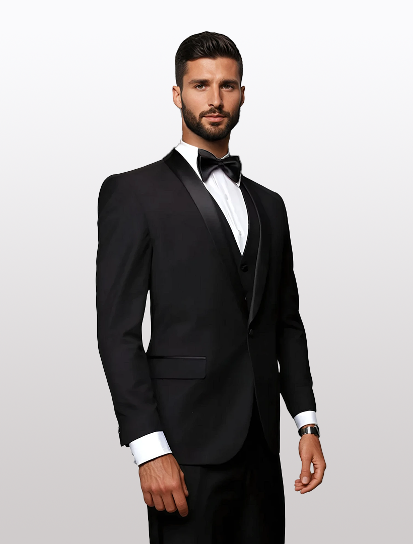 A man in a sleek Statement Men's Black with Black Lapel Vested 100% Wool Tuxedo and bow tie stands against a plain white background, highlighting the elegance of its tailored fit.