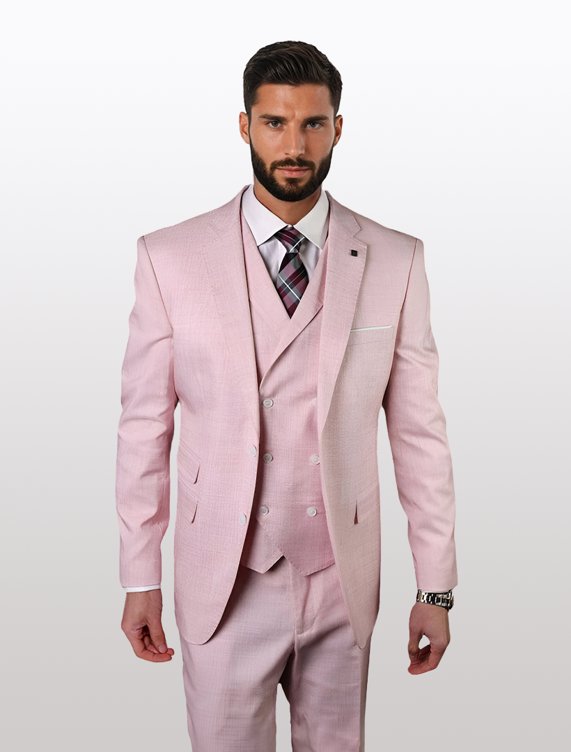 A man stands against a white backdrop wearing a Statement men's dusty pink suit, featuring 100% wool and a double-breasted vest, in a slim fit. He completes his look with a white shirt and plaid tie.