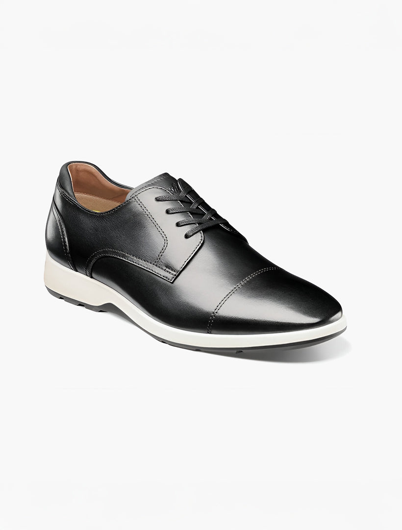 The Florsheim Transit Cap Toe Oxford Black Shoe features a black leather lace-up design, white sole, rounded toe, and visible stitching. Ideal for men’s casual walking. Displayed on a plain white background. Brand: Florsheim.