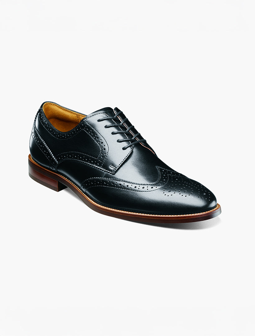 The Florsheim Black Wingtip Oxford Shoe features genuine leather, brogue detailing, a brown sole, and Flexsole Technology. Shown on a white background.