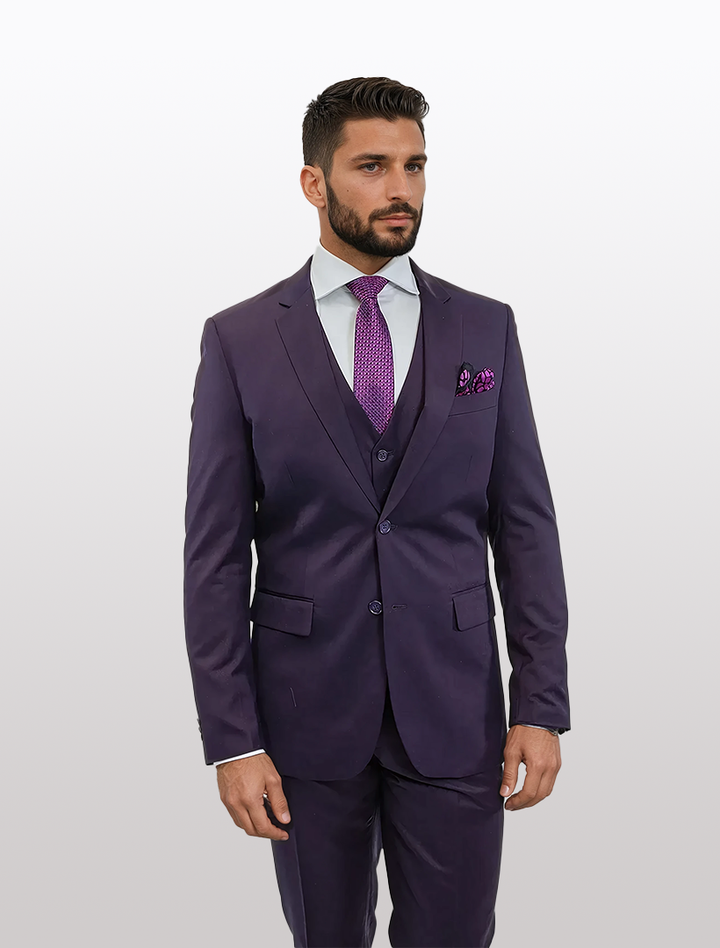 A man in the FUBU Purple Vested Suit by Fubu The Colle poses confidently against a white background, with a matching tie and pocket square. The slender Tetron Rayon fabric and stretch armhole ensure comfort and flawless style.