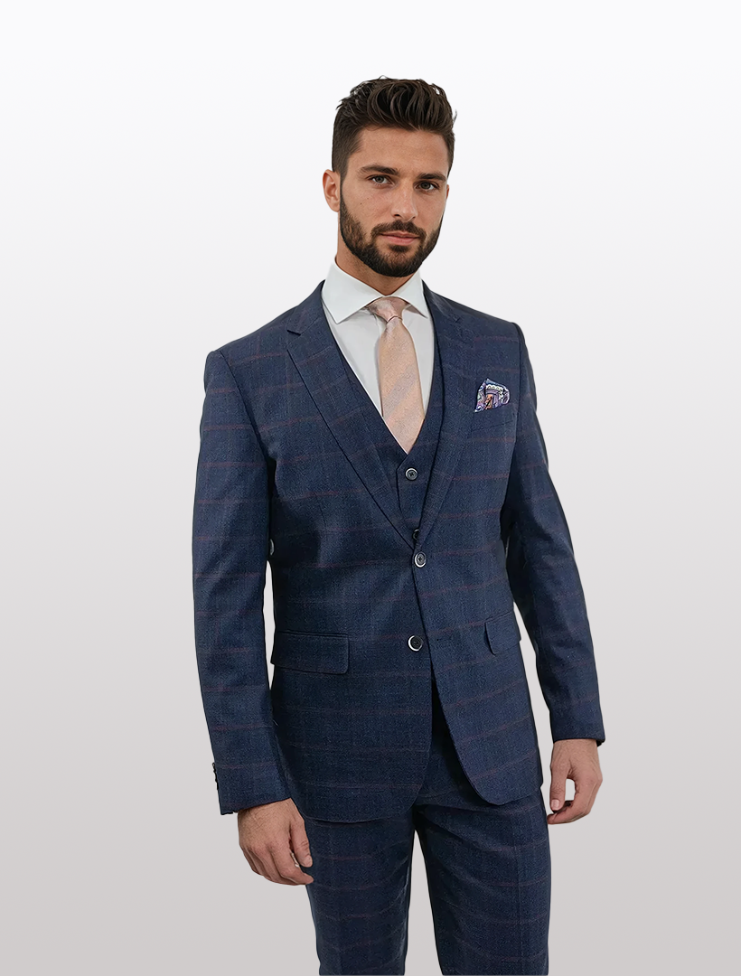 A man wears the FUBU Dark Blue and Burgundy Windowpane Vested Suit by Fubu The Colle with a white shirt and light pink tie, highlighting the comfort of stretch armholes, against a plain background.