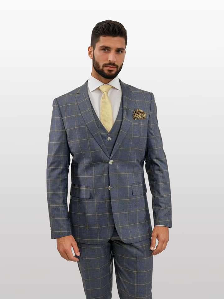 In a sleek grey madras vested suit by Fubu The Colle, a man pairs the ensemble with a yellow tie and pocket square against a plain background. The suit is tailored from Tetron Rayon and features stretch armholes for comfort and mobility.