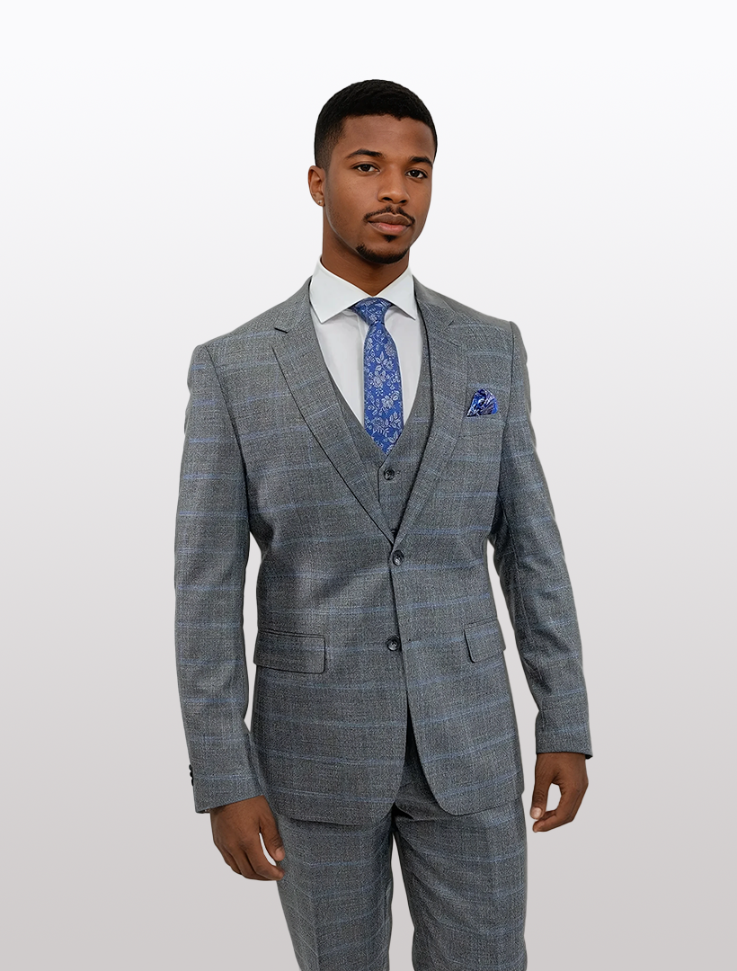 A man wearing a FUBU Grey Crosshatch with Blue Windowpane Vested Suit from Fubu The Colle, complemented by a blue tie and pocket square, stands against a plain background.
