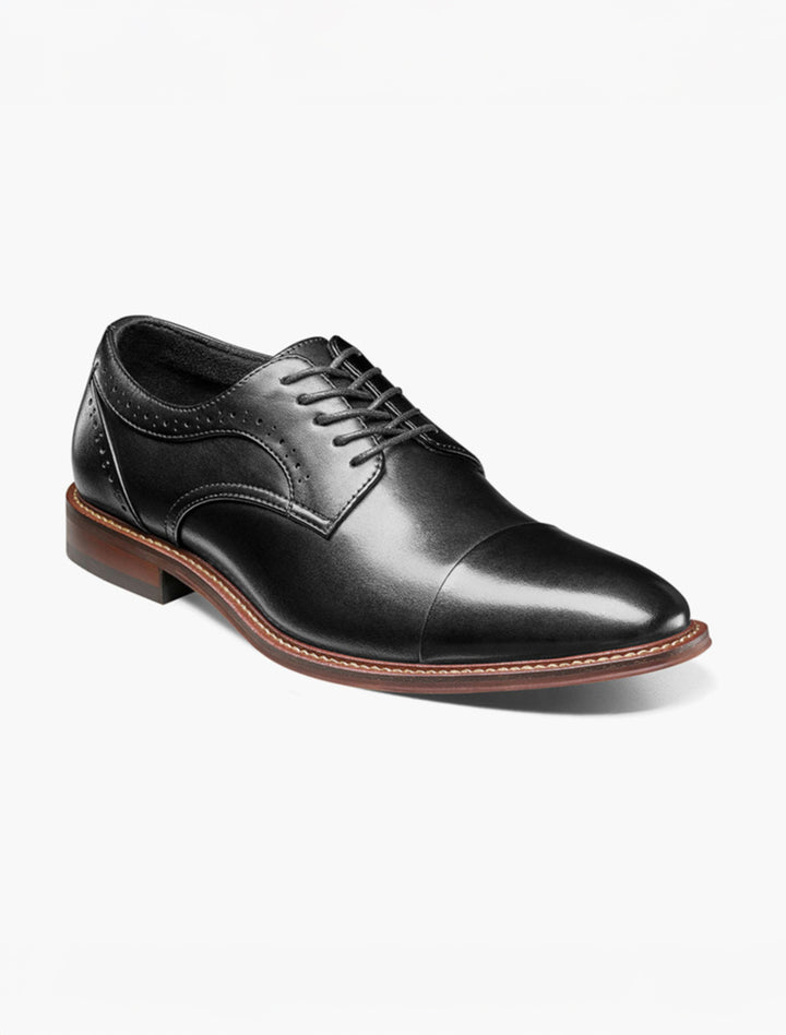 The Stacy Adams Black Maddox Cap Toe Oxford Shoes feature black leather, a brown sole, closed lacing, anatomical arch support, and subtle side brogue details, shown against a white background.