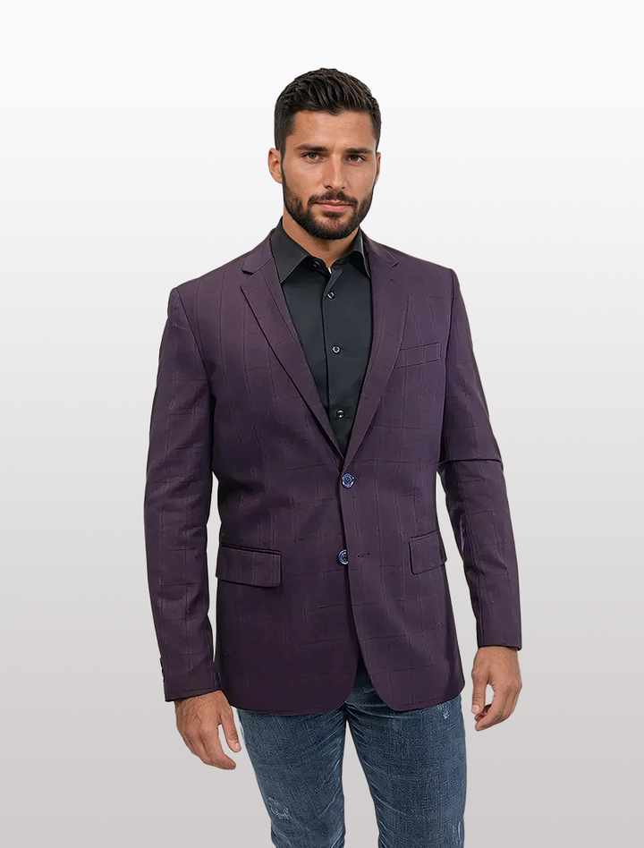 A man confidently poses in a Fubu The Colle Slim Fit Burgundy Windowpane Sport Jacket over a black shirt and jeans against a plain white background.