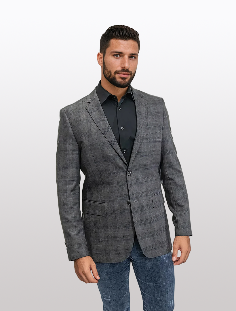 A man in a slim fit brown Glen check sport jacket by Fubu The Colle, paired with a black shirt and jeans, stands against a light gray background.