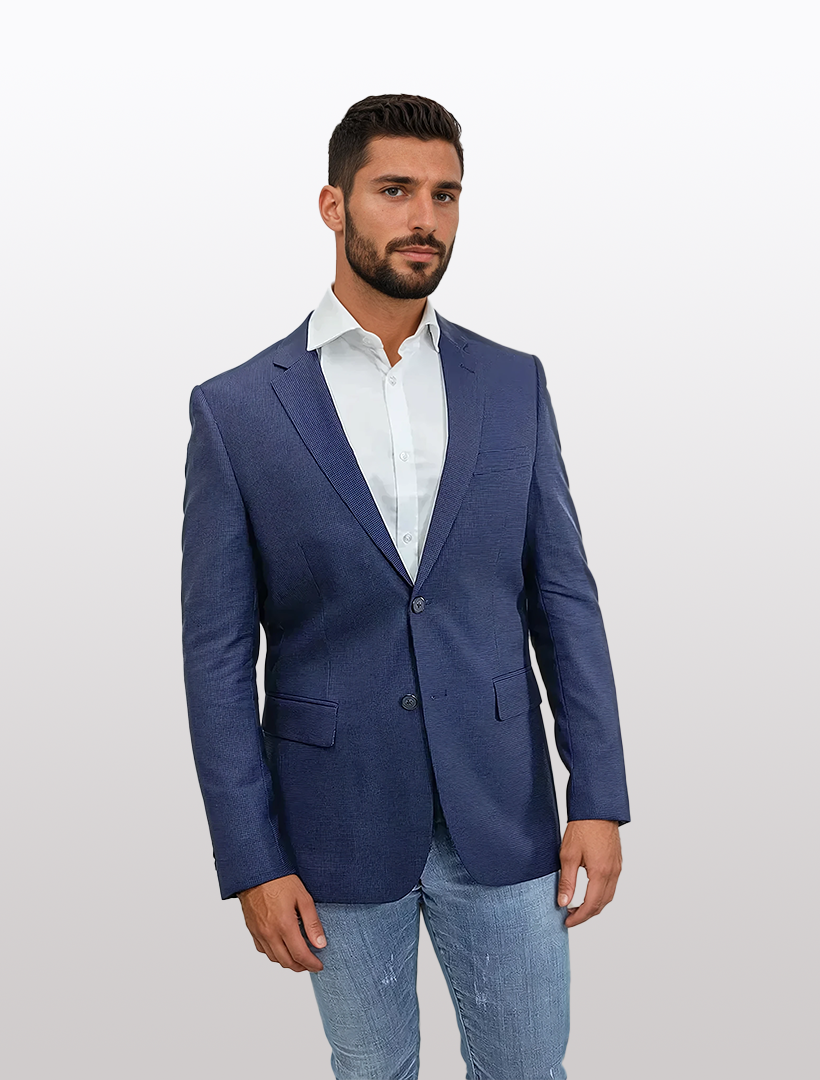 A man wearing a FUBU Slim Fit Blue Houndstooth Sport Jacket by Fubu The Colle and jeans stands against a plain background.