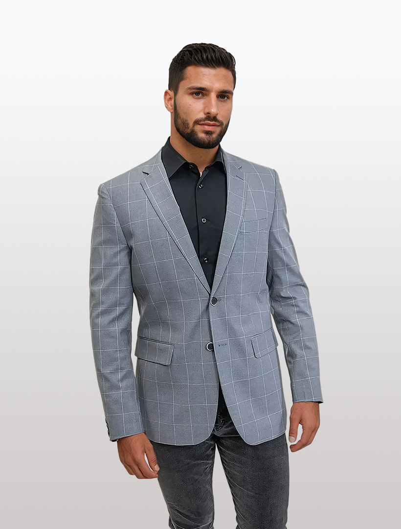 A man stands against a white backdrop wearing the FUBU Slim Fit Light Grey Windowpane Sport Jacket and a black shirt, offering timeless elegance with a modern twist.