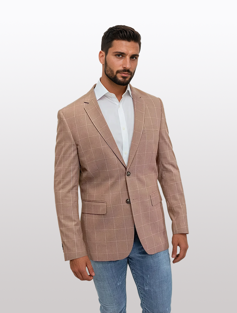 A man in a FUBU Slim Fit Light Brown Windowpane Sport Jacket from Fubu The Colle, paired with a white shirt and blue jeans, stands against a plain background.