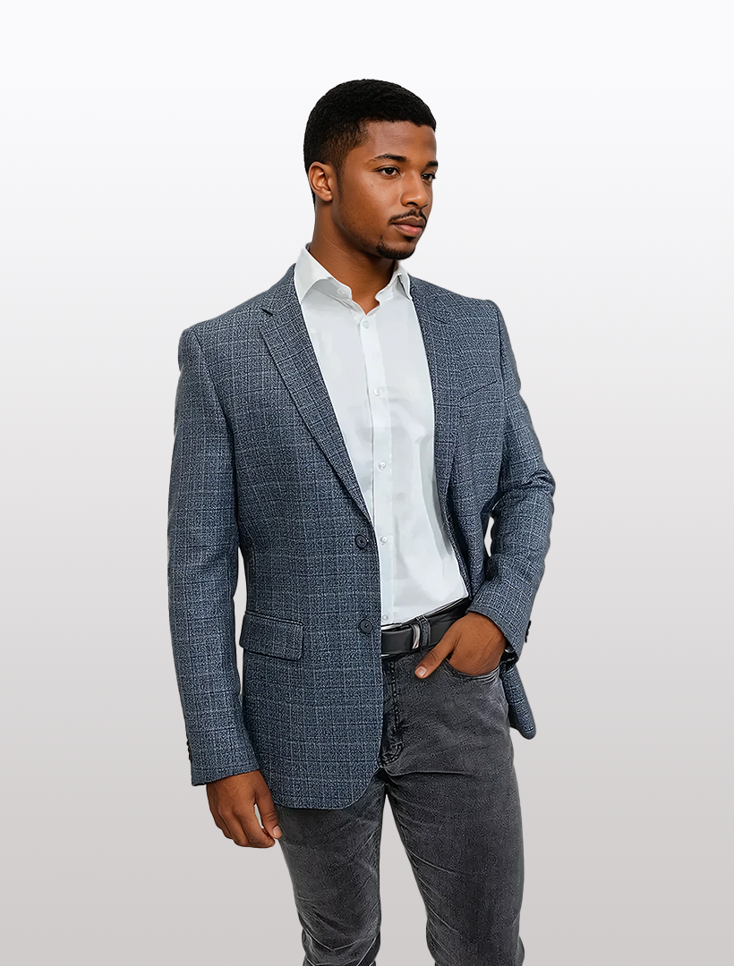 The man exudes confidence, dressed in a FUBU Slim Fit Black Graphic Knit Sport Jacket by Fubu The Colle, paired with a crisp white shirt and gray pants. With one hand casually in his pocket, he stands poised against a plain background.