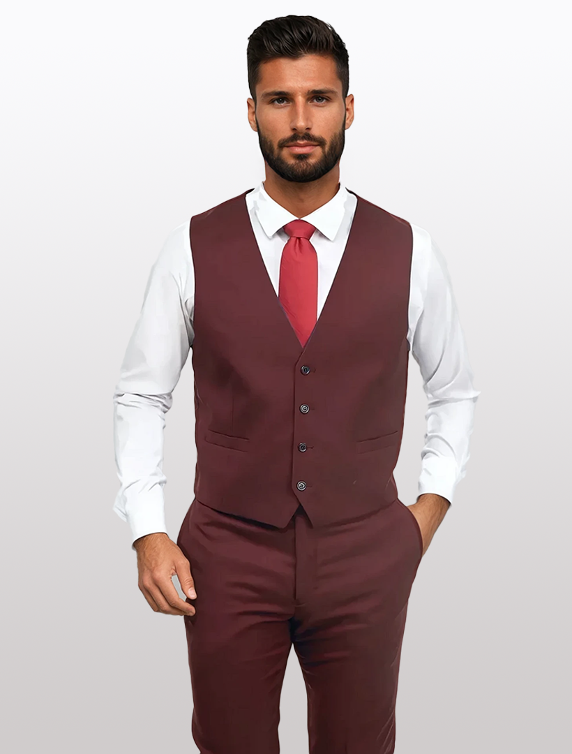 A man confidently stands against a plain background, wearing a Couture 1910 Men's Burgundy Suit Vest made from high-performance stretch Tetron Rayon. He pairs it with a white shirt and red tie, the slim-fit design enhancing his sharp look.