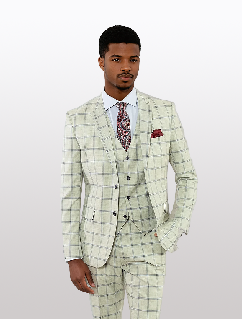 A man in a FUBU Light Grey and Navy Double Windowpane Vested Suit by Fubu The Colle, paired with a paisley tie, stands against a plain background.