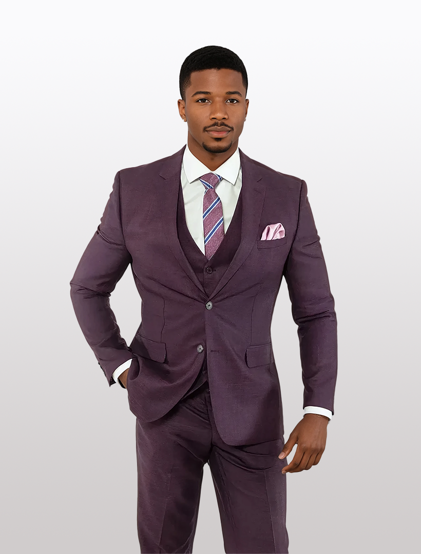 A man in a FUBU Purple Solid Vested Suit by Fubu The Colle, paired with a striped tie and pocket square, stands against a plain background.