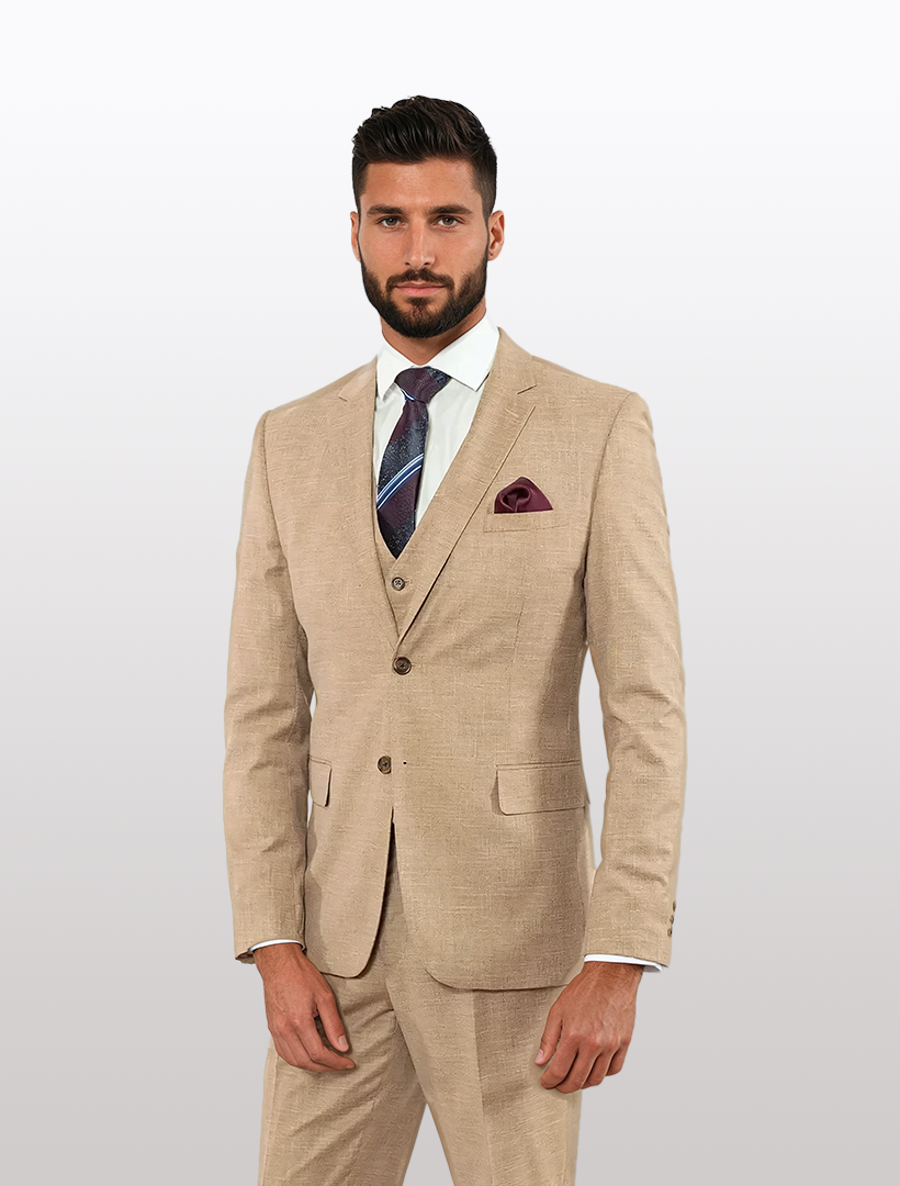 A man in a modern fit FUBU Dusty Pink Solid Vested Suit with a white shirt, purple tie, and pocket square stands against a plain background, showcasing the polished look of its stretch armhole design by Fubu The Colle.