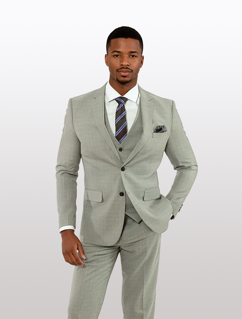 A man in a FUBU Light Grey Solid Vested Suit by Fubu The Colle, featuring a modern fit with stretch armholes, wears it with a white shirt and striped tie, standing against a plain background.