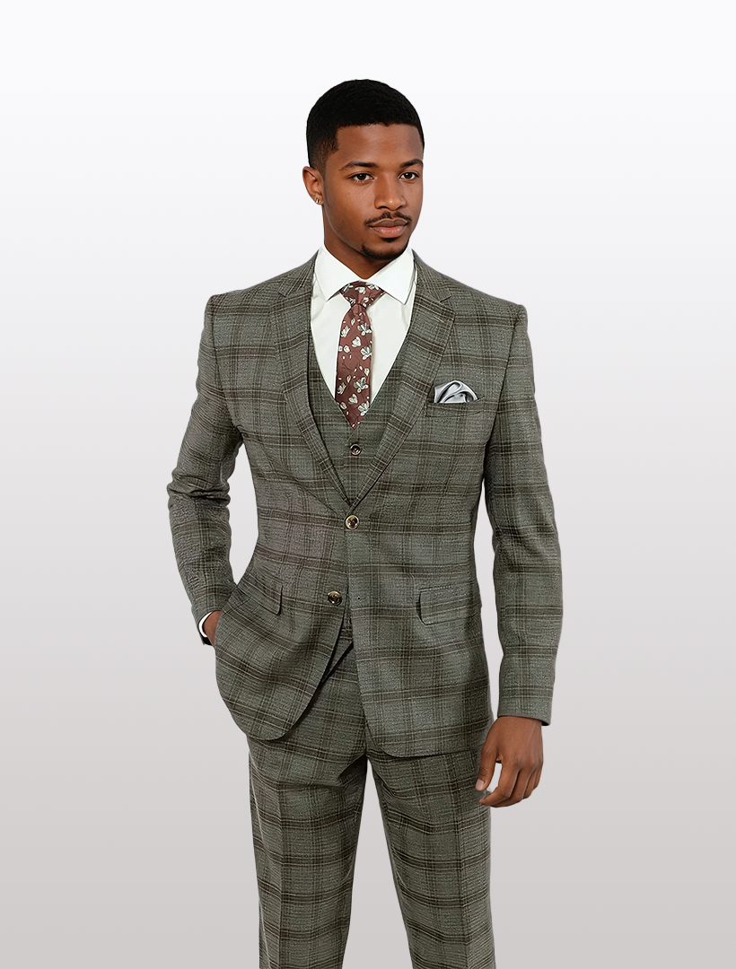 A man stands against a plain background wearing the FUBU Charcoal with Brown Plaid Vested Suit by Fubu The Colle, paired with a patterned tie and pocket square.