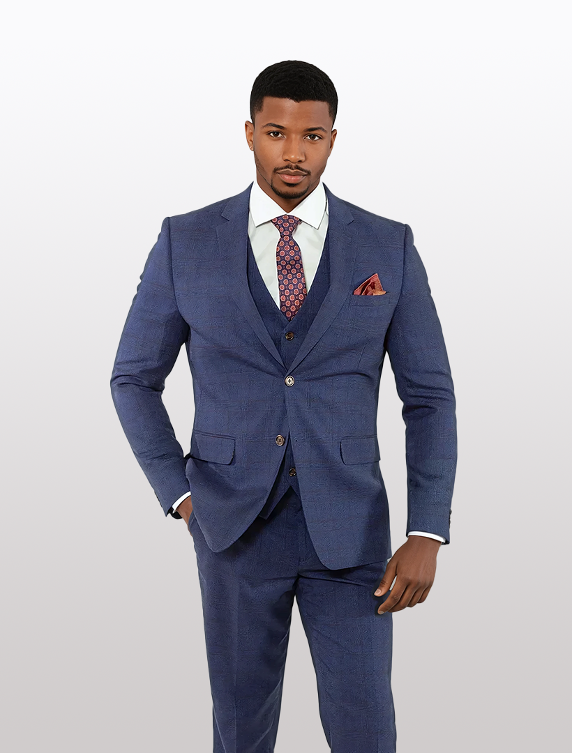A man in a FUBU Navy with Brown Double Windowpane Vested Suit by Fubu The Colle, complemented by a white shirt, patterned tie, and pocket square, stands against a plain background.