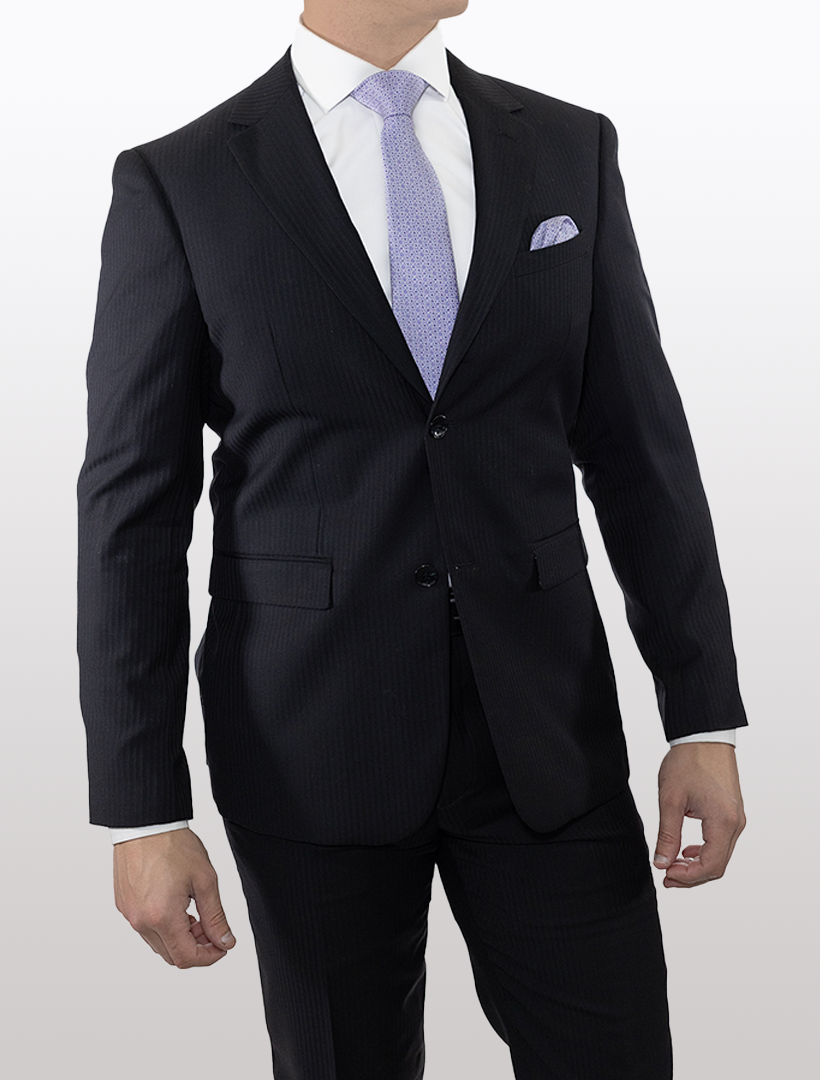 A man wearing a Douglas Grahame Men's Black Textured Chalk Stripe Wool Slim Fit Suit and a light purple tie stands against a plain background.