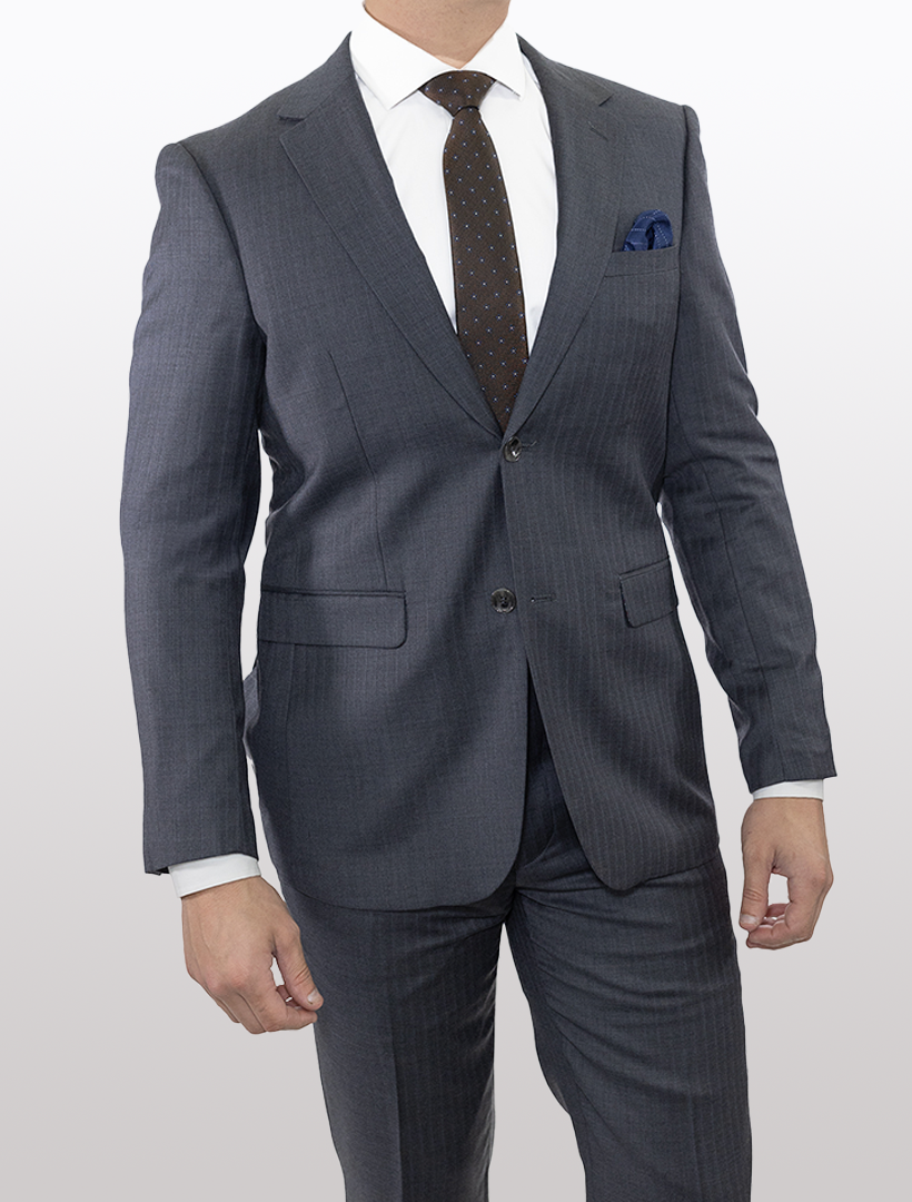 A person wearing a Douglas Grahame Men's Grey Double Stripe Wool Slim Fit Suit, complemented by a white shirt and dark tie, is standing against a plain background.