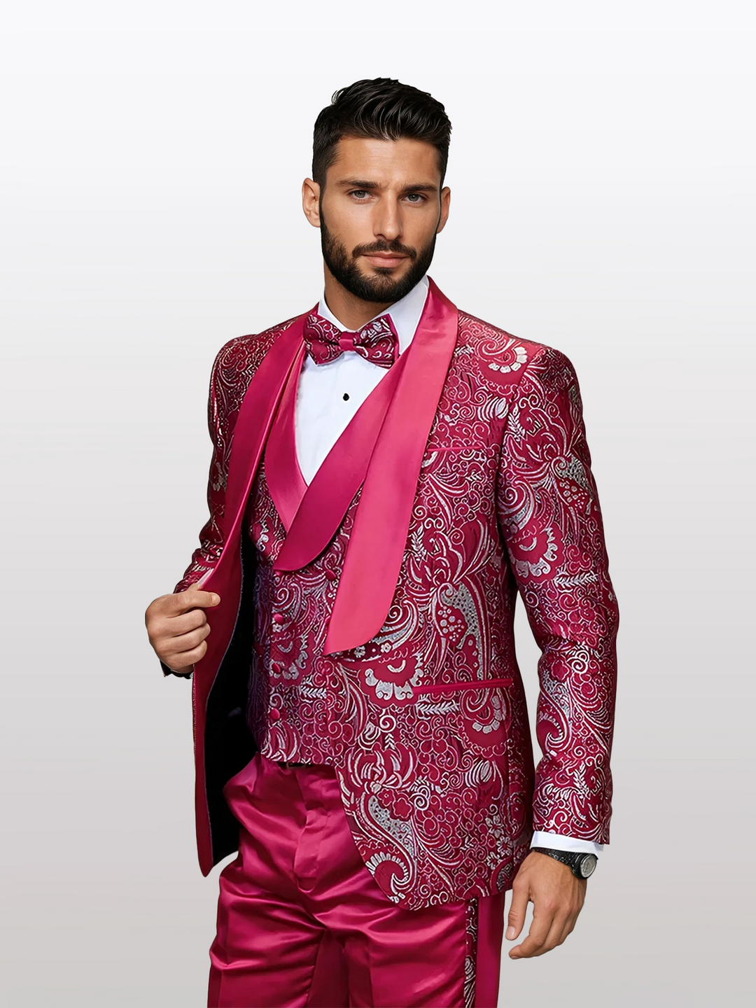 A man in a Statement Men's Red Patterned Vested Tuxedo, featuring a matching bow tie and waistcoat over a crisp white shirt, exudes elegance and confidence. This tailored ensemble is crafted from 100% wool.