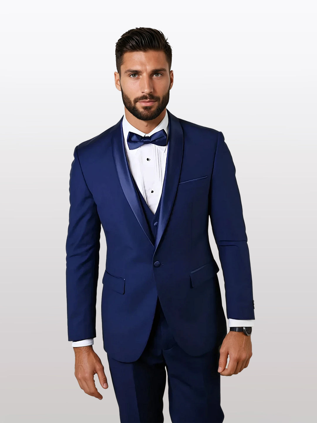 A man with dark hair and a beard stands against a plain background, wearing the Statement Men's Sapphire Shawl Vested Tuxedo by Statement, impeccably tailored in navy blue for a perfect fit and crafted from 100% wool.