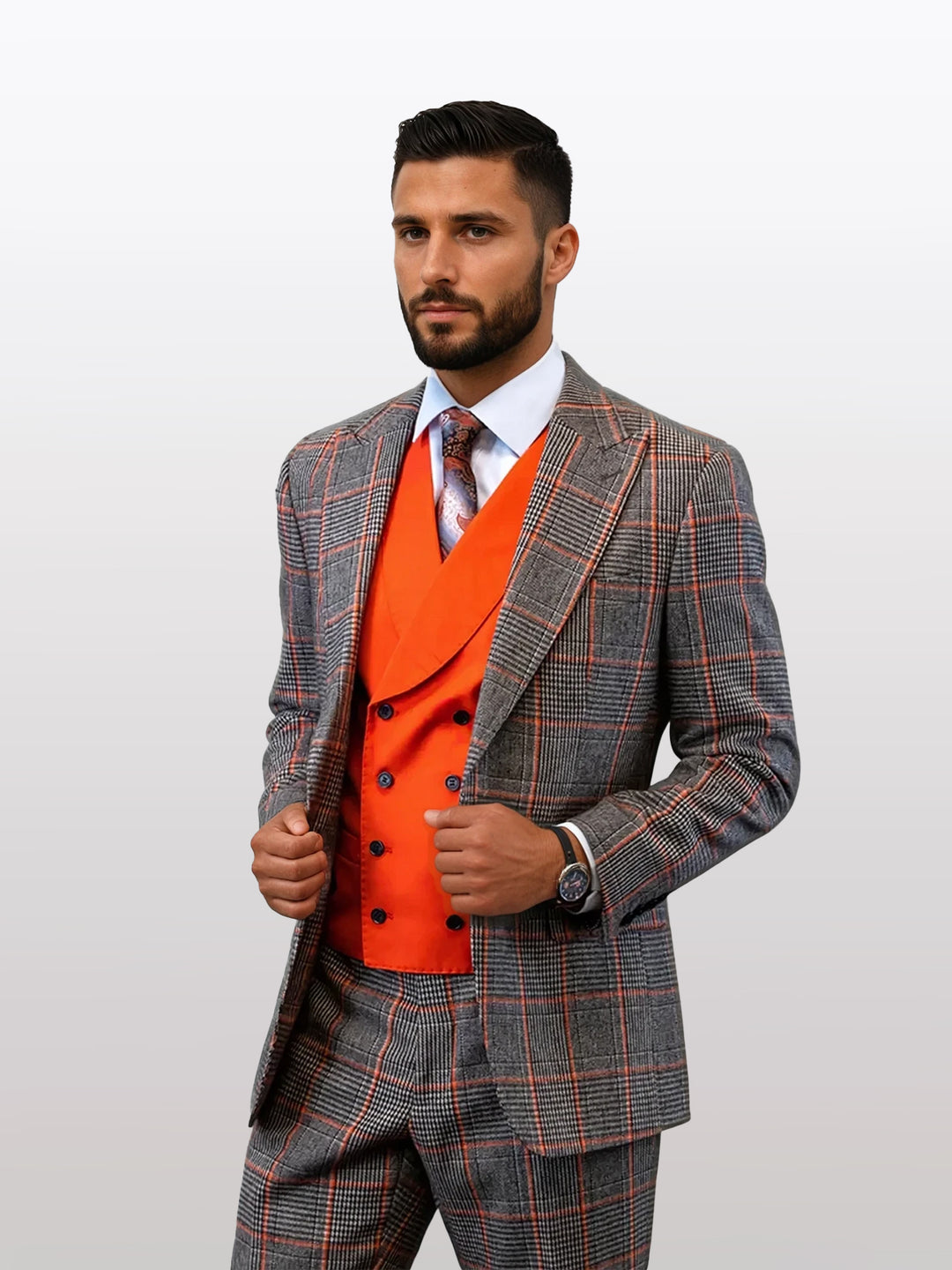A man models the Statement Men's Coral Over Plaid Suit made from 100% wool, featuring a gray and orange plaid design with an orange double-breasted vest and tie, all against a plain background.