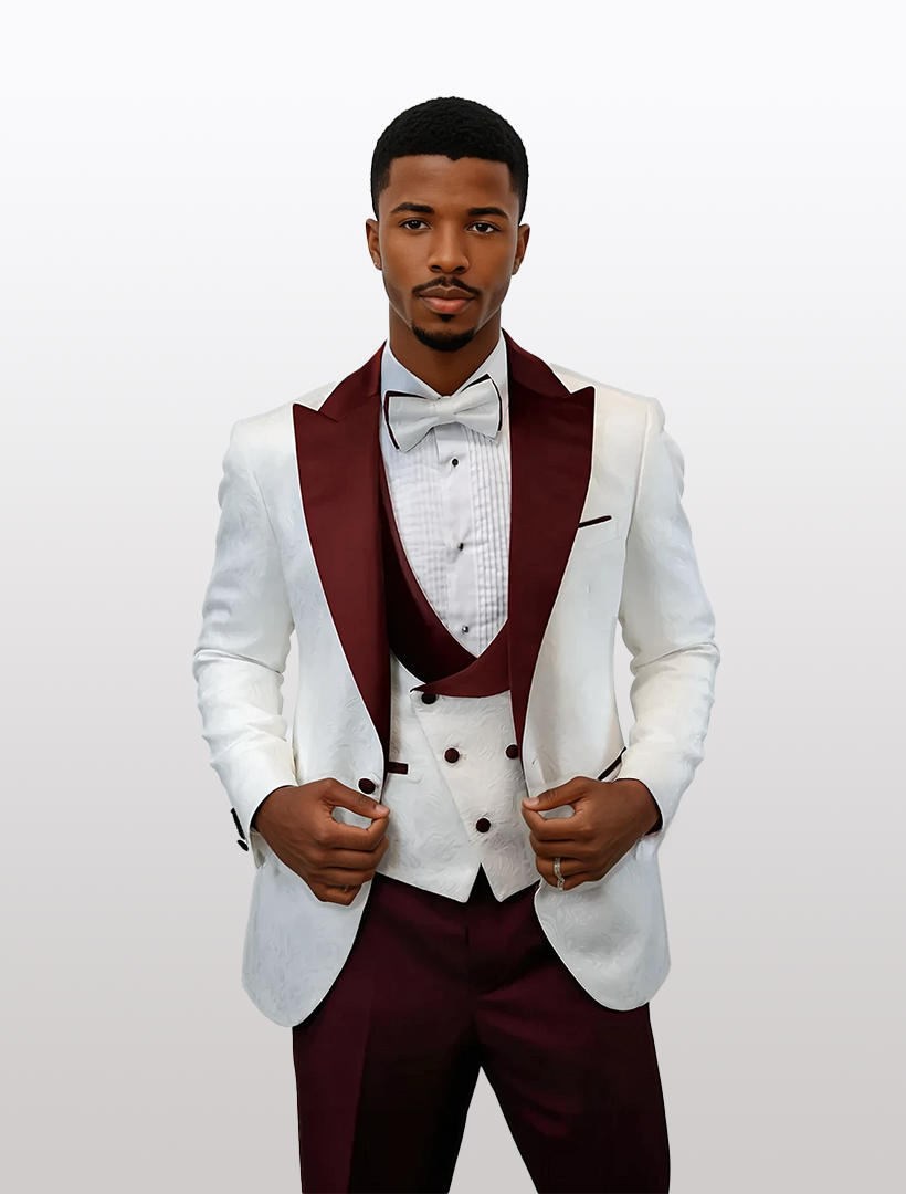 A man dons the Statement Men's White with Burgundy Peak Lapels Vested Tuxedo, exuding elegance and sophistication. The modern fit tuxedo, crafted from 100% wool with a bow tie, effortlessly blends timeless style with contemporary flair against a plain backdrop.