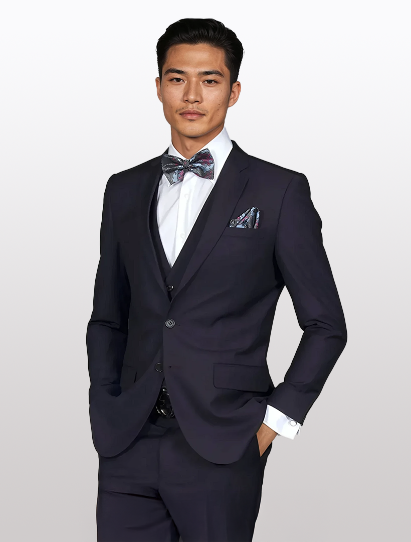 A man in the Statement Men's Eggplant Slim Fit Vested Suit, tailored from 100% wool and finished with a floral bow tie and pocket square, stands against a plain background.