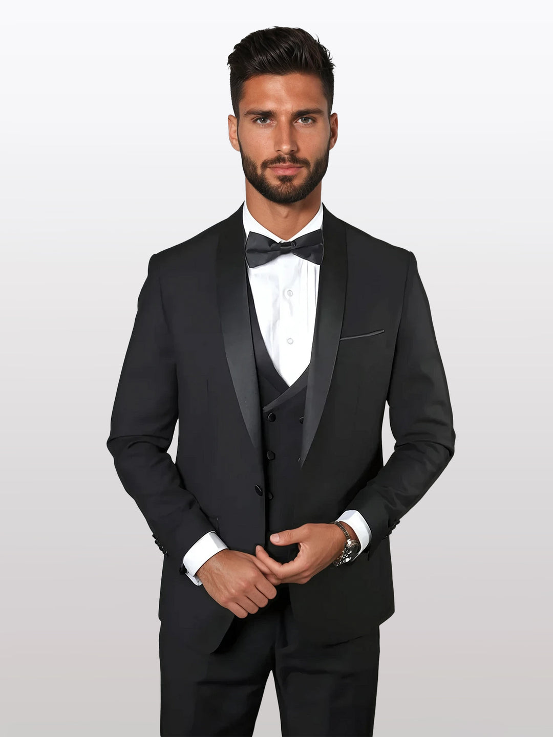 A man in a tailored Statement Men's Black Shawl Lapel 100% Wool Vested Tuxedo is dressed in a crisp white shirt and bow tie, skillfully adjusting his jacket.