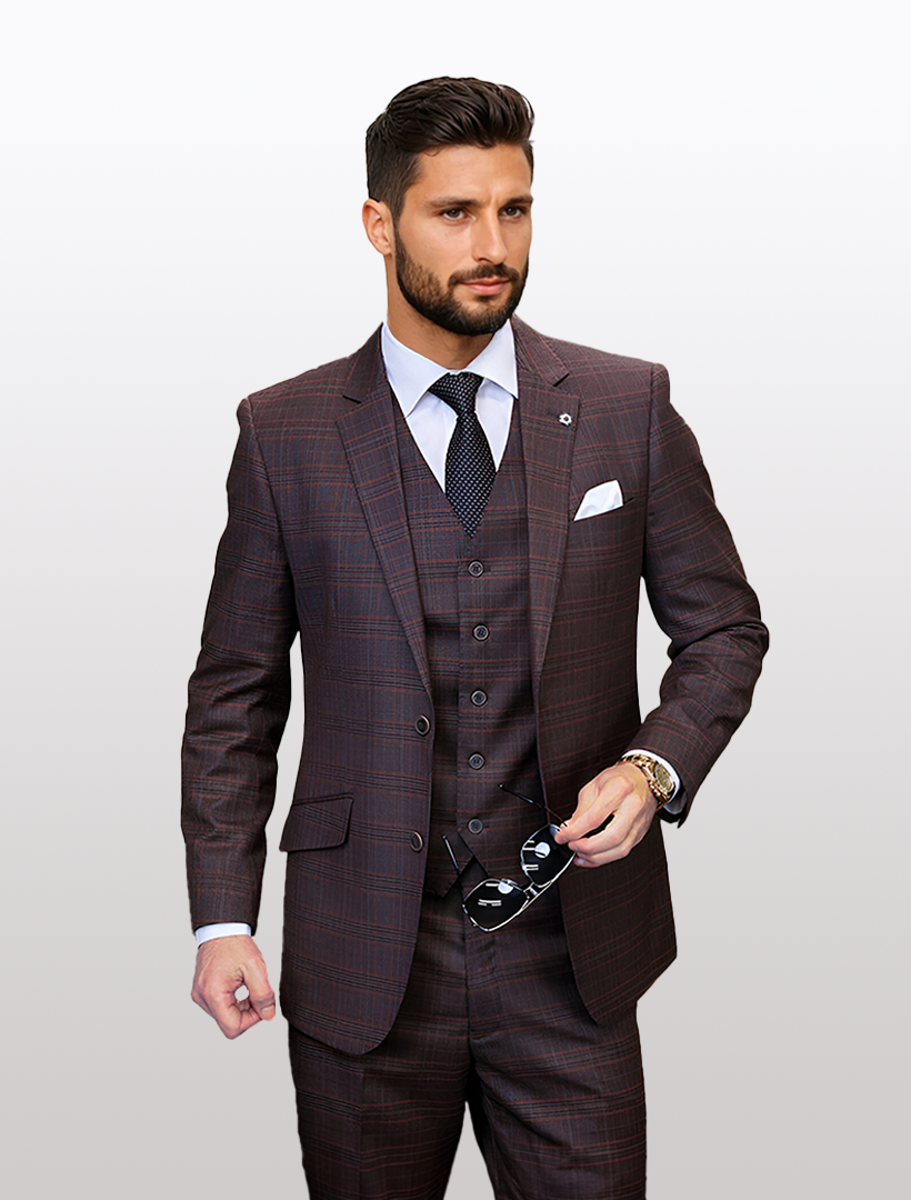A man in a modern fit Statement Men's Copper Plaid Vested Suit, featuring 100% wool and stretch armhole comfort, wears a black tie and holds sunglasses while facing forward against a plain background. The suit combines classic style with contemporary ease.