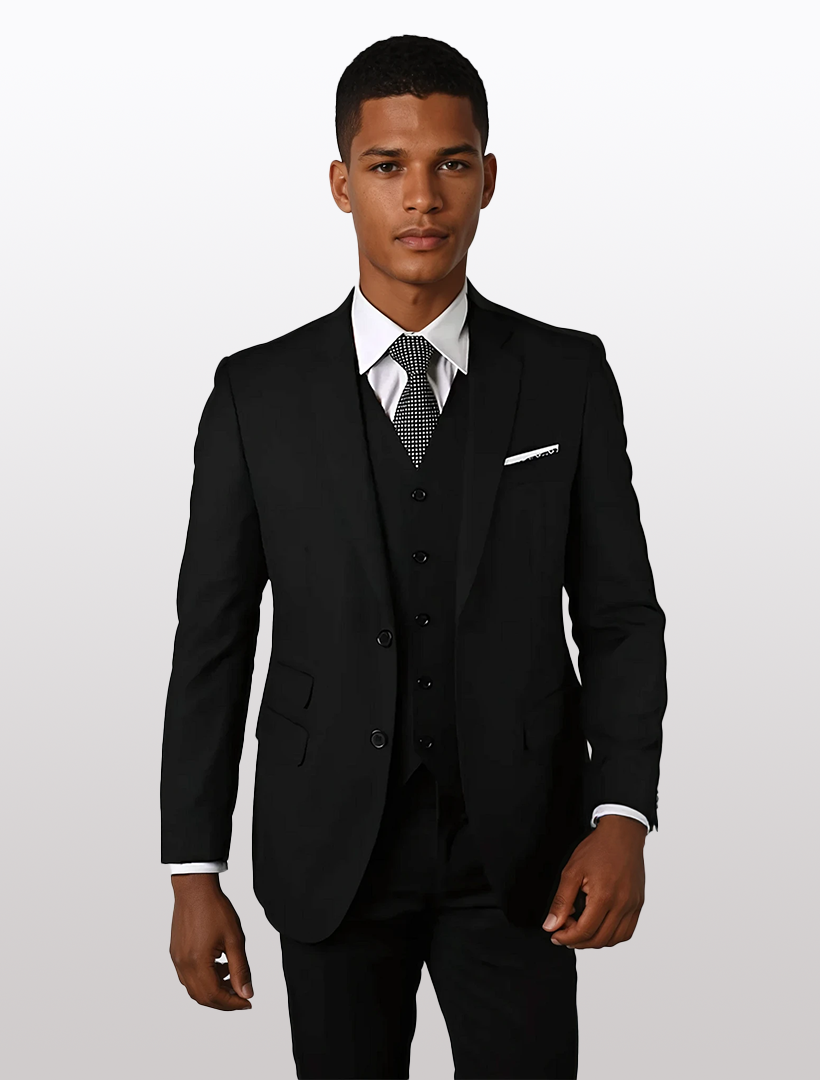 A person wearing a Statement Men's Solid Black Tailored Fit 100% Wool Vested Suit, paired with a white shirt, patterned tie, and pocket square stands against a plain background.